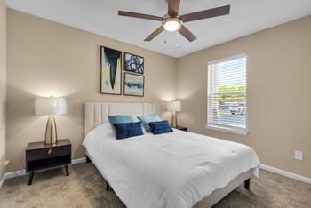 A carpeted bedroom with a ceiling fan and window.